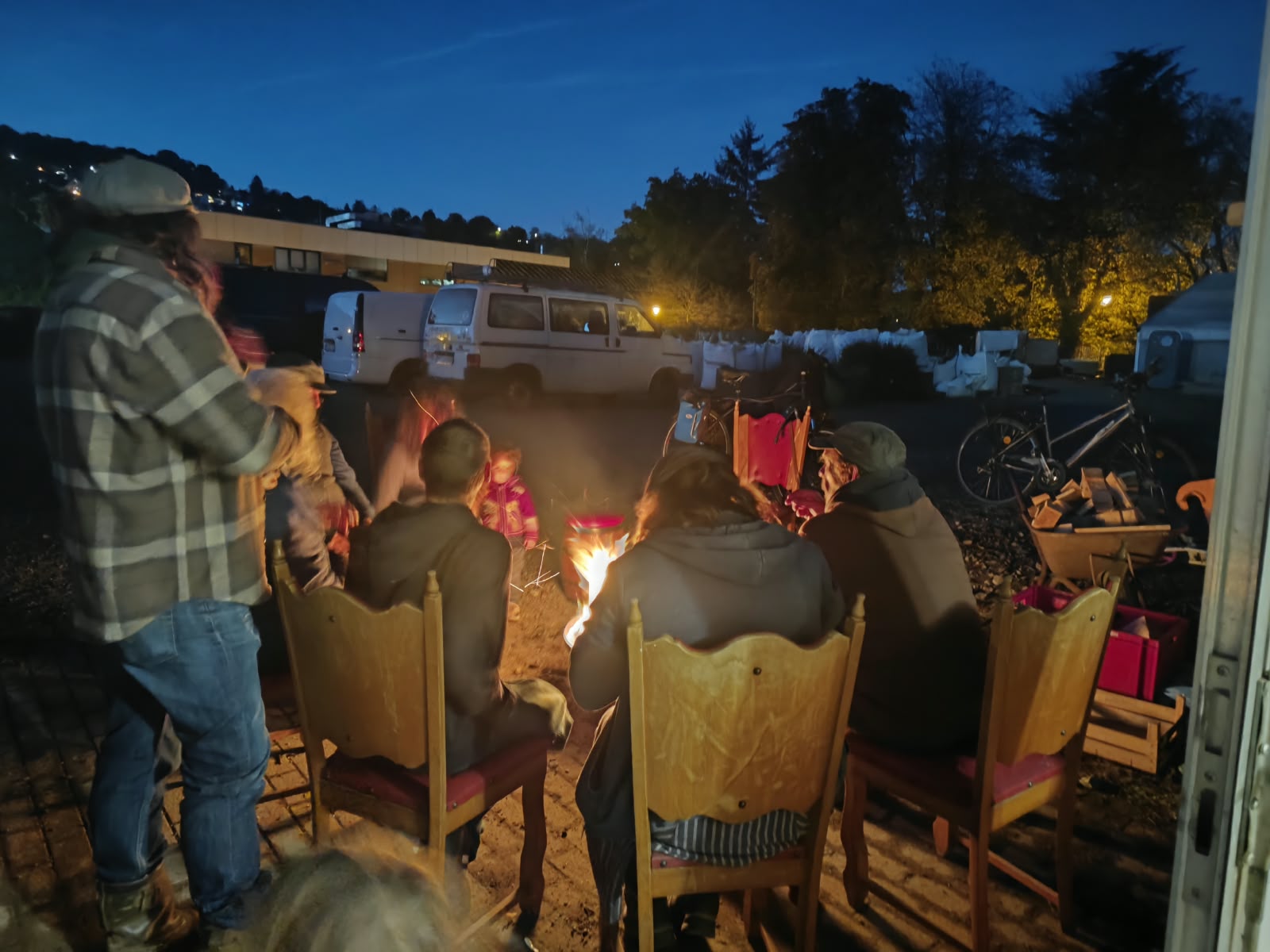Gruppe sitzt am Abend gemeinsam an einer Feuerschale