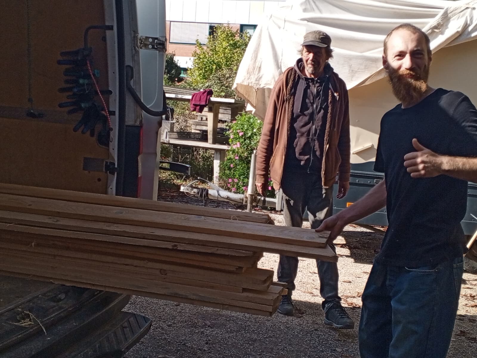 Helfer beim Ausladen langer Holzbretter aus dem Fahrzeug