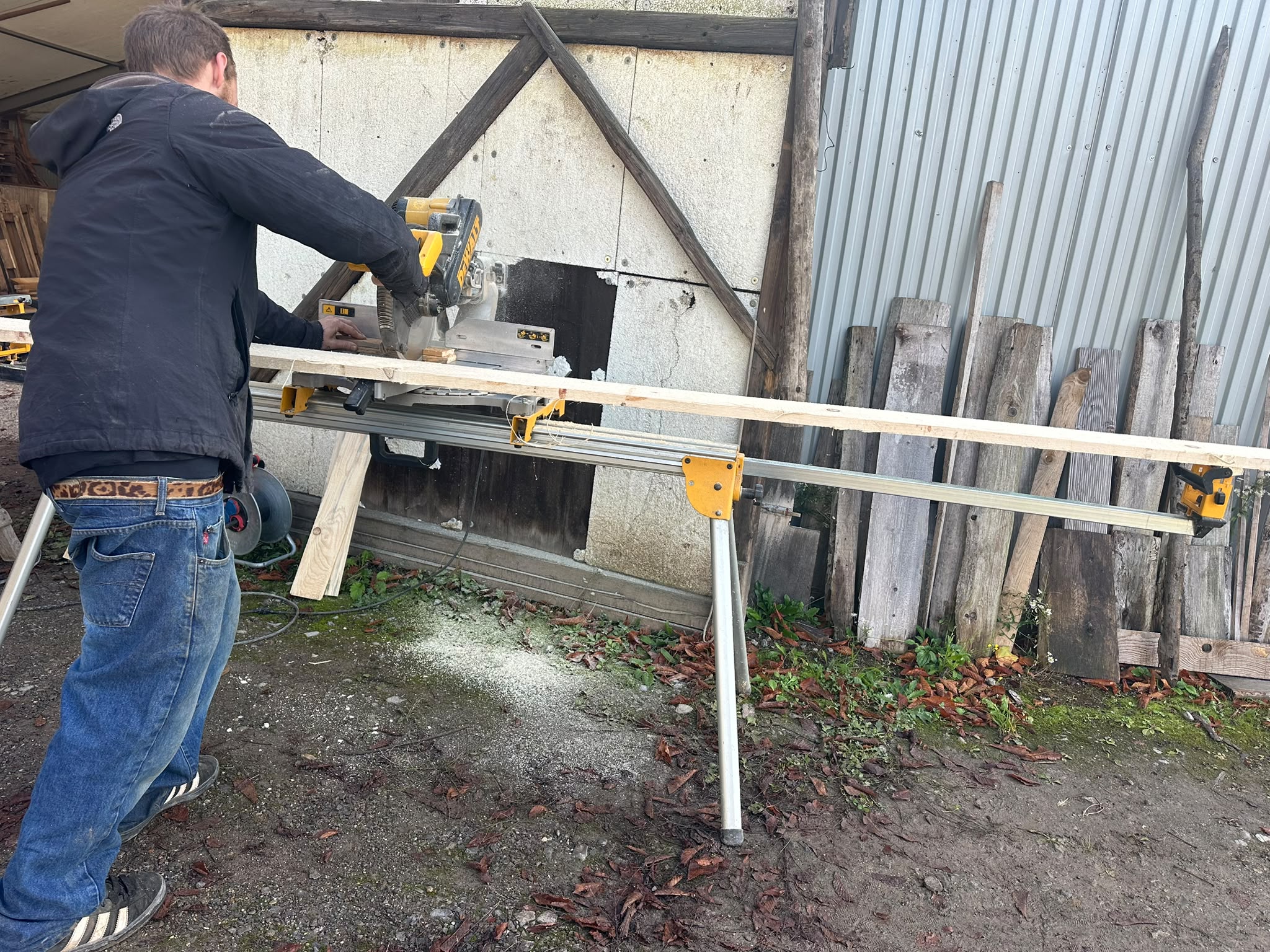 Helfer sägt einen Holzbalken mit einer Kappsäge zurecht